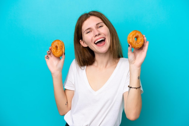 Joven inglesa aislada de fondo azul sosteniendo donuts con expresión feliz