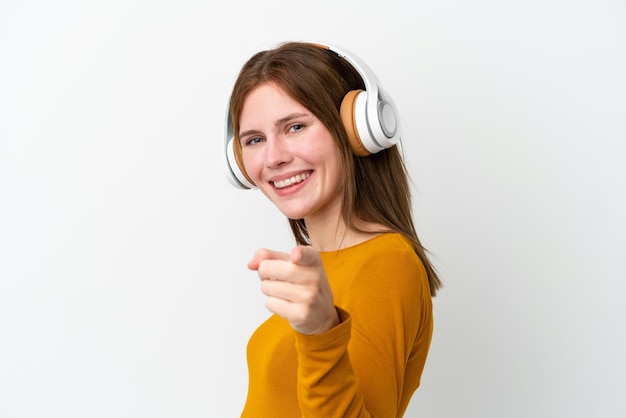 Joven inglesa aislada de fondo blanco escuchando música y apuntando al frente