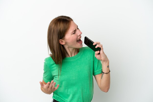 Foto joven inglesa aislada de fondo blanco usando teléfono móvil y cantando