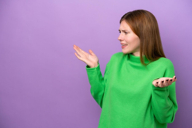 Joven inglesa aislada de fondo morado con expresión de sorpresa mientras mira de lado