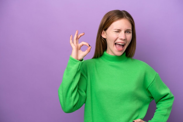 Joven inglesa aislada de fondo morado mostrando el signo de ok con los dedos