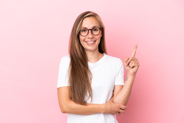 Joven inglesa aislada de fondo rosa feliz y apuntando hacia arriba