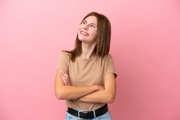 Joven inglesa aislada de fondo rosa mirando hacia arriba mientras sonríe