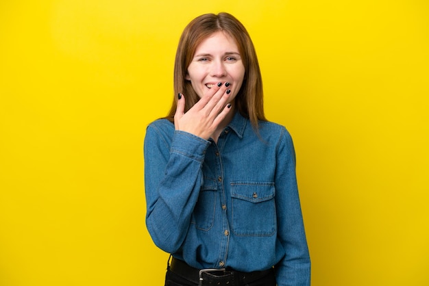 Joven inglesa aislada sobre fondo amarillo feliz y sonriente cubriendo la boca con la mano