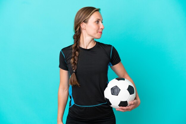 Joven inglesa aislada sobre fondo azul con balón de fútbol