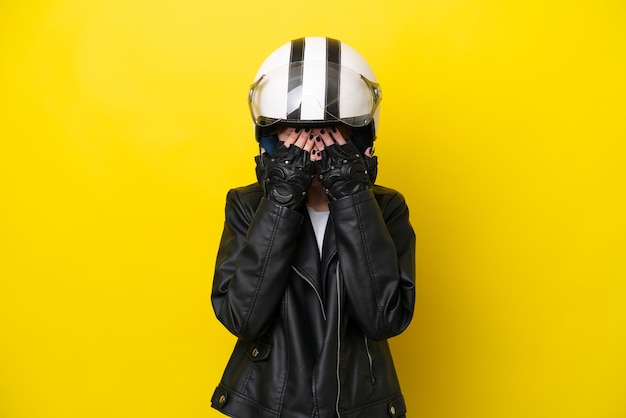 Joven inglesa con casco de motocicleta aislada de fondo amarillo con expresión cansada y enferma