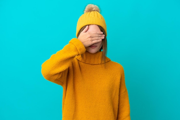 Joven inglesa con chaqueta de invierno aislada de fondo azul cubriendo los ojos con las manos. no quiero ver algo