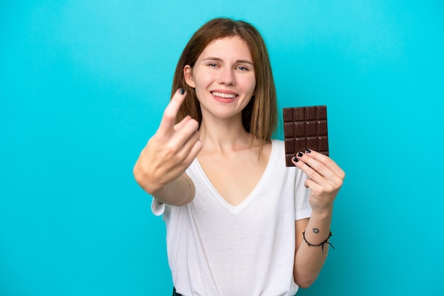 Joven inglesa con chocolat aislado de fondo azul haciendo el gesto de venir