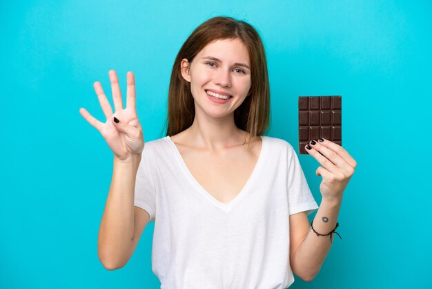 Joven inglesa con chocolate aislada de fondo azul feliz y contando cuatro con los dedos