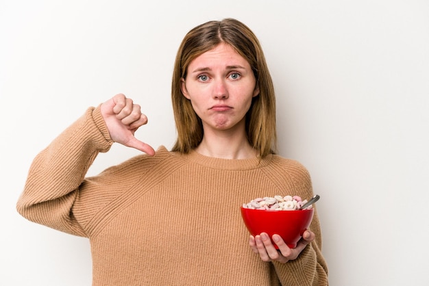 Joven inglesa comiendo cereales aislada de fondo blanco mostrando un gesto de aversión pulgares hacia abajo Concepto de desacuerdo