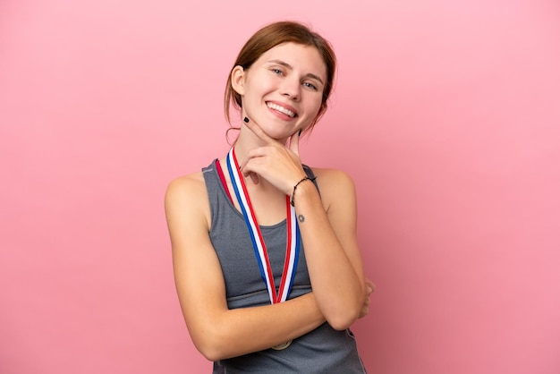 Joven inglesa con medallas aisladas sobre fondo rosa sonriendo