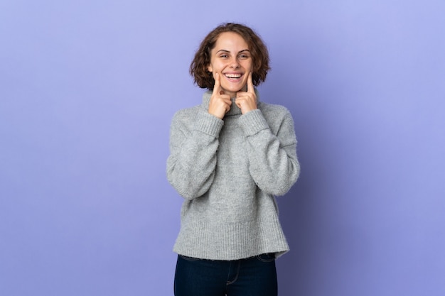 Joven inglesa sobre fondo morado sonriendo con una expresión feliz y agradable