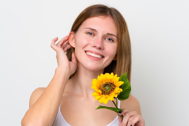 Joven inglesa sosteniendo un girasol mientras sonríe Cerrar retrato