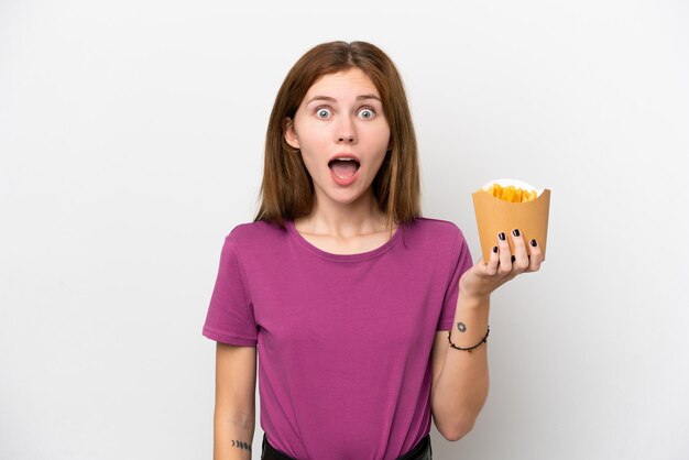 Joven inglesa sosteniendo patatas fritas aisladas de fondo blanco con expresión facial sorpresa