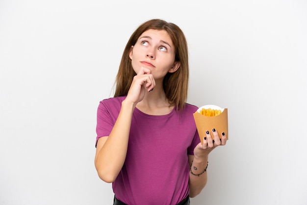 Joven inglesa sosteniendo patatas fritas aisladas de fondo blanco y mirando hacia arriba