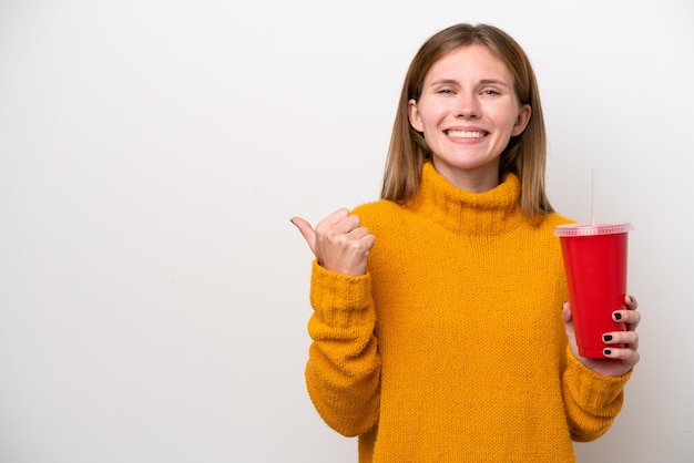 Joven inglesa sosteniendo soda aislada de fondo blanco apuntando hacia un lado para presentar un producto