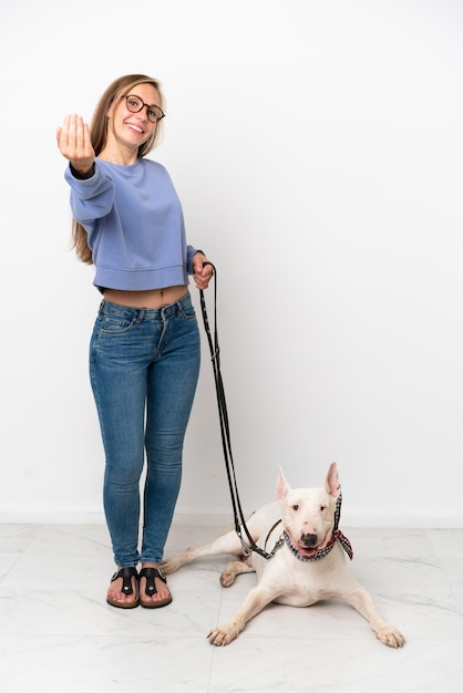 Joven inglesa con su perro aislado de fondo blanco invitando a venir con la mano Feliz de que hayas venido