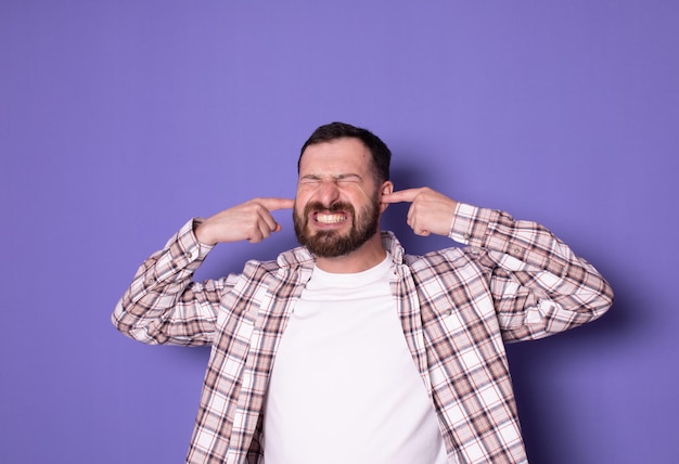 Foto joven insatisfecho molesto barbudo hombre caucásico ojos cerrados orejas cubiertas