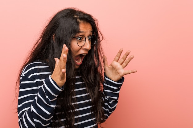 Joven intelectual india grita fuerte, mantiene los ojos abiertos y las manos tensas.