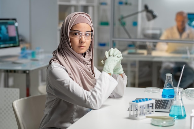 Joven investigadora contemporánea en anteojos protectores e hiyab