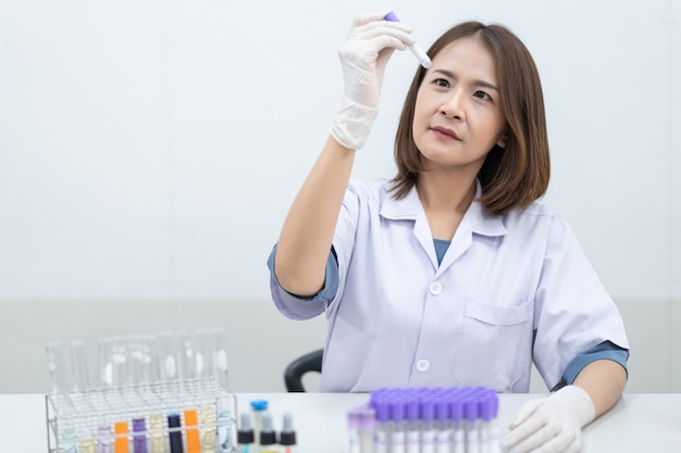 Una joven investigadora, médica, científica o asistente de laboratorio que trabaja con tubos médicos de plástico para investigar y examinar experimentos científicos en un laboratorio moderno. Educación foto de stock