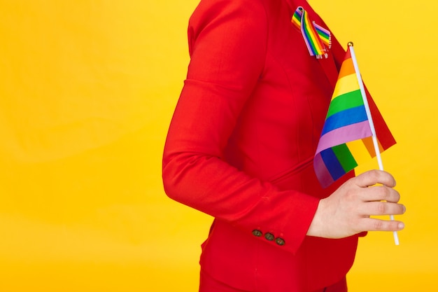 Joven irreconocible con pequeña bandera LGBT