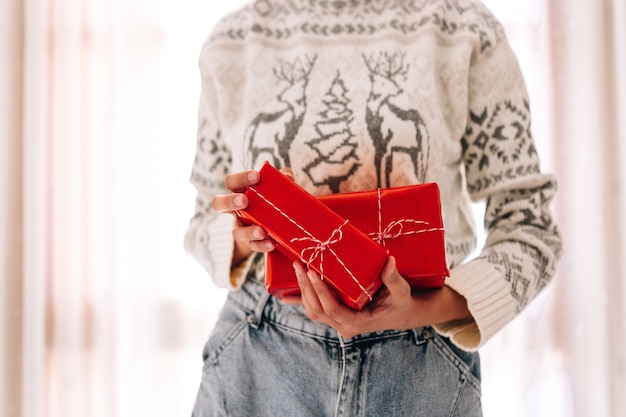 Joven irreconocible sostiene en una caja de regalo en papel rojo.