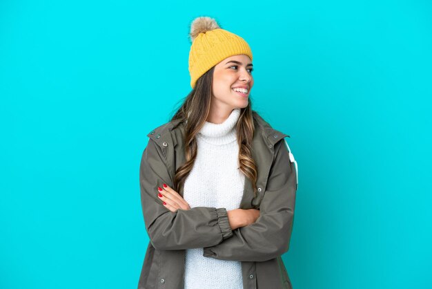 Joven italiana con chaqueta de invierno y sombrero aislado de fondo azul mirando hacia el lado