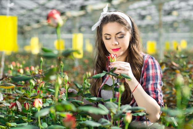 La joven jardinera o trabajadora de invernadero cuida las flores en el invernadero