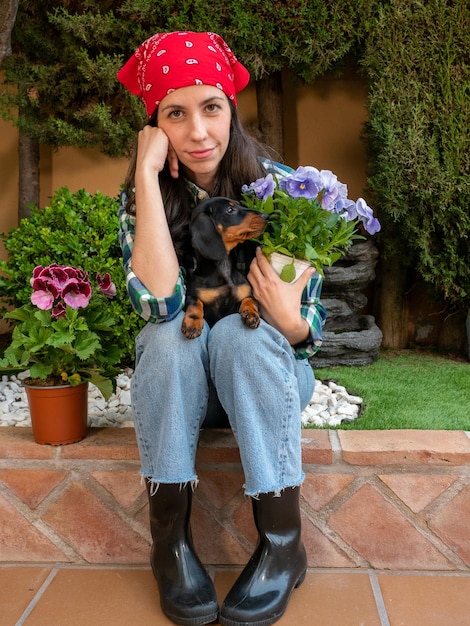 Joven Jardinería en casa con su perrito teckel