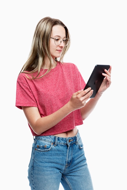 Una joven en jeans con una tableta en sus manos. . Vertical.
