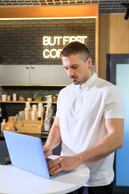 Un joven jefe trabaja en una computadora portátil en un punto de café de oficina