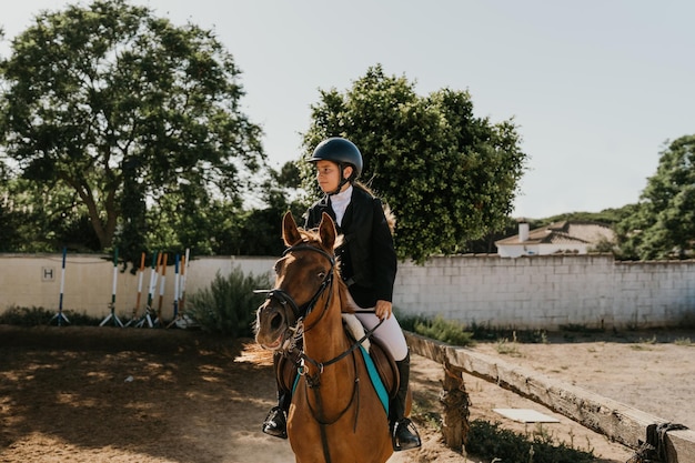 Joven jinete trotando un caballo en una escuela de equitación