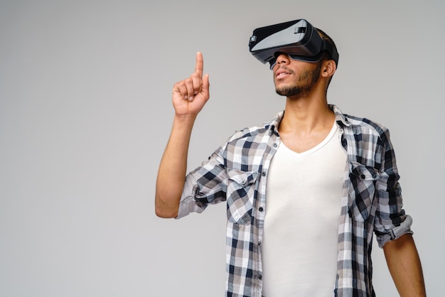 Joven joven con casco de realidad virtual vr sobre pared gris claro