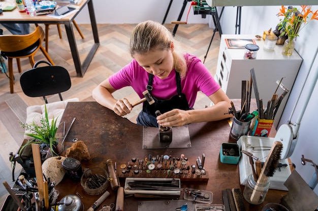 Joven joyería que hace joyas en el taller