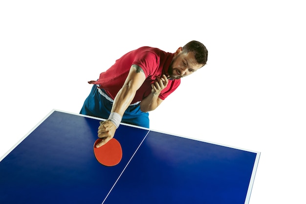 Joven juega al ping pong en la pared blanca.