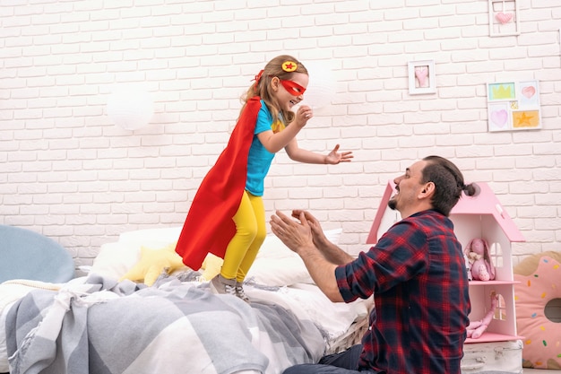 Joven juega con su hija en superhéroes en la sala.