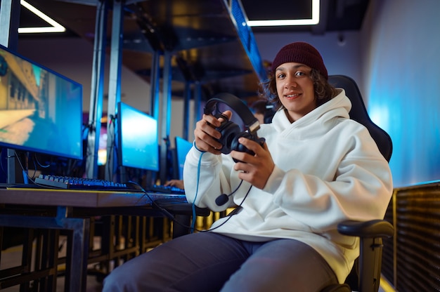 Joven jugador alegre tiene auriculares en el club de juegos