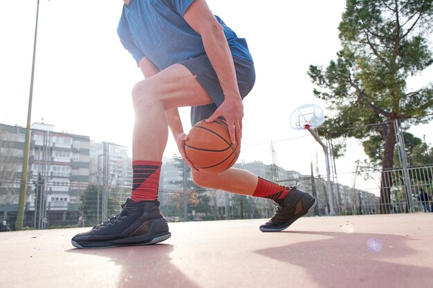 Joven jugador de baloncesto callejero regateando con el balón en el concepto de entrenamiento de la cancha