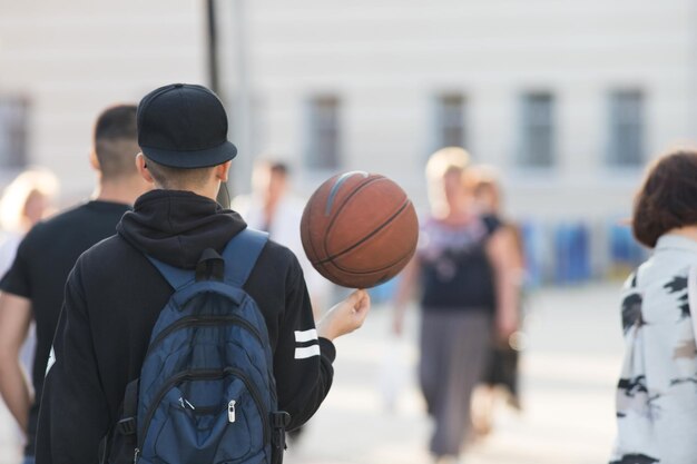 Joven jugador de baloncesto caminando por la calle con el balón