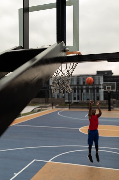 Joven jugador de baloncesto jugando baloncesto en la cancha de baloncestro