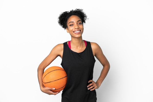 Joven jugador de baloncesto mujer latina aislada sobre fondo blanco posando con los brazos en la cadera y sonriendo