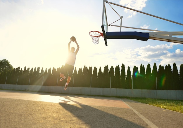 Un joven jugador de baloncesto que vuela hacia el aro para hacer una volcada