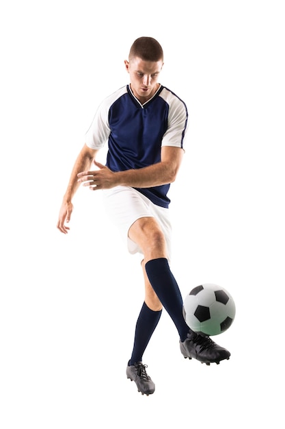 Foto un joven jugador caucásico confiado pateando la pelota contra un fondo blanco