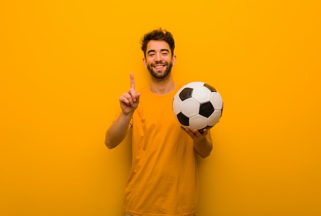 Joven jugador de fútbol hombre mostrando número uno