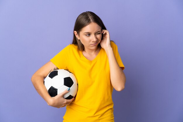 Joven jugador de fútbol lituano mujer aislada sobre fondo púrpura frustrado y cubriendo las orejas