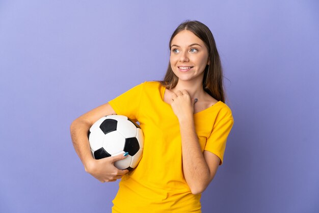 Joven jugador de fútbol lituano mujer aislada sobre fondo púrpura mirando hacia arriba mientras sonríe