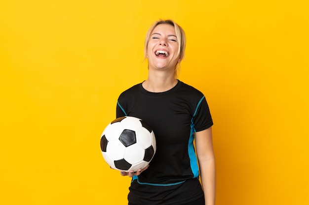 Joven jugador de fútbol ruso mujer aislada sobre fondo amarillo riendo