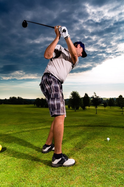 Joven jugador de golf en curso haciendo swing de golf