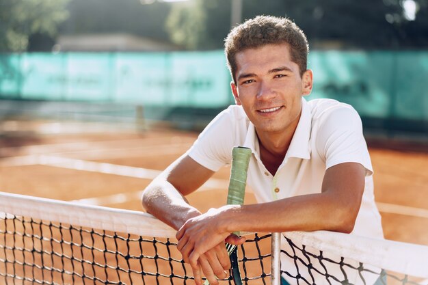 Joven jugador de tenis de raza mixta con pie de raqueta en la cancha de tenis